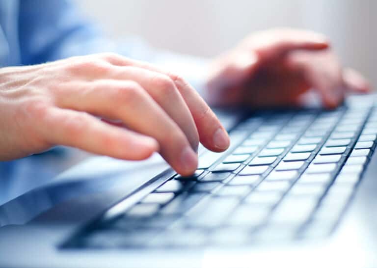 Hånd, der skriver på en computer med fokus på tastaturet.